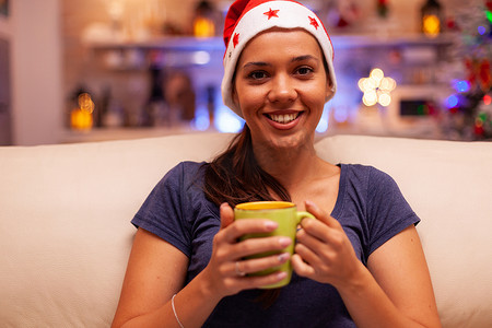 圣诞派礼摄影照片_戴着红色圣诞帽的女人手里拿着一杯咖啡的画像