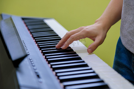 钢琴作曲家摄影照片_弹电子钢琴的女孩的手。