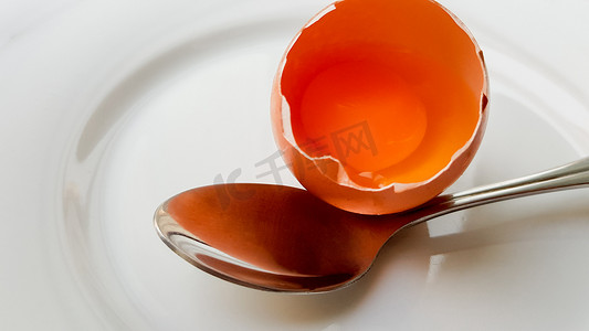 白盘子和勺子特写中的碎鸡蛋。