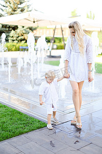 年轻的白人母亲带着小孩在喷泉附近散步。