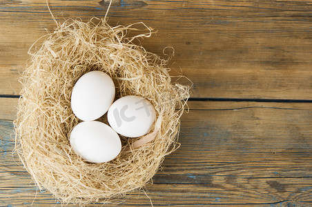 木桌上的巢里有白色的鸡蛋，有复制空间