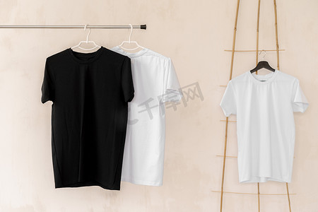 T恤设计摄影照片_衣架上的白色和黑色 T 恤用于设计展示