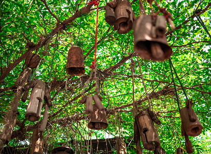 手工制作的木制牛颈铃挂在树上，用于花园装饰。