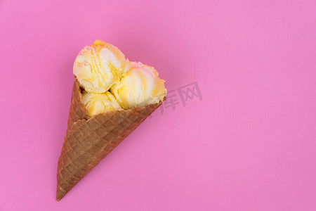 粉红色背景的华夫蛋筒中的水果香味冰淇淋球。