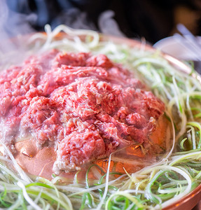 首尔韩国餐厅的牛肉烧烤烤肉，铜锅上的生活方式新鲜韩国美食，配上葱片，特写，复制空间