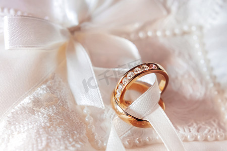金色婚礼装饰摄影照片_织物上镶有钻石的金色结婚戒指。