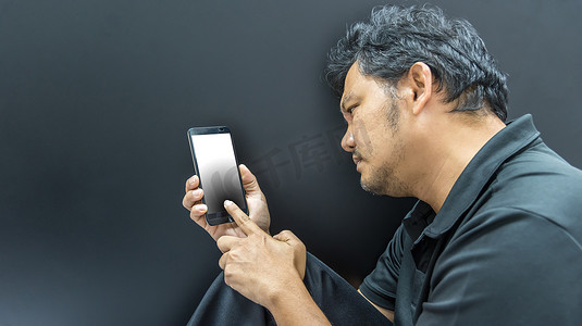 人体工程学摄影照片_亚洲男子在黑暗风格中使用智能手机