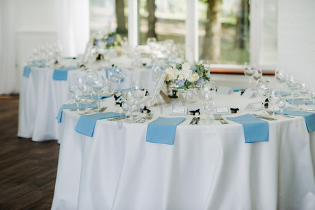 蓝色的花朵摄影照片_婚礼餐桌装饰，餐桌上有蓝色的花朵，在餐厅餐桌装饰中用于婚礼晚餐。