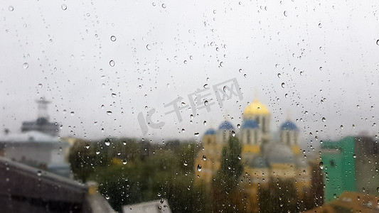 多云天气下，秋季城市背景上有滴的湿窗。