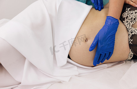 理疗师在担架上给孕妇按摩肚子。