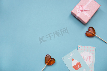 蓝色背景上的红心、礼物和贺卡形式的棒棒糖。