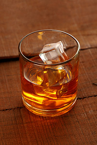 冰镇冰块摄影照片_木桌上加冰块的冰镇威士忌酒杯