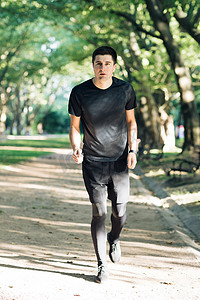 成年男子在户外跑步使用无线蓝牙耳机听音乐与 smartwatch 享受健康。