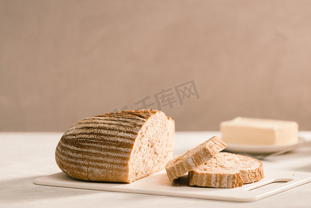 盘子架上的面包，周围是白桌上的黄油和牛奶，特写