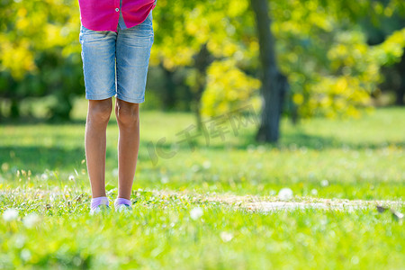 孩子们的脚踩在公园的草坪上。