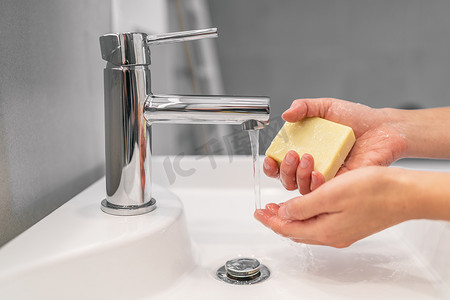 阻止冠状病毒摄影照片_用肥皂洗手 20 秒手部卫生妇女手持肥皂条以预防 COVID-19 冠状病毒，以阻止冠状病毒的传播