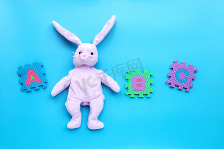 立方体的兔子摄影照片_蓝色背景上有英文字母拼图的兔子玩具。