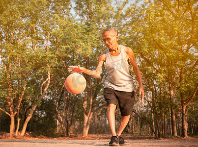 夏日，亚洲老人在操场上打篮球。