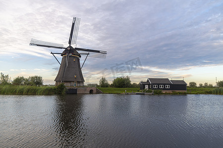 荷兰风车沿着运河铺设，日落时分，强风吹动野草