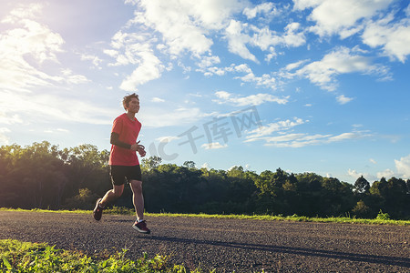 公路奔跑摄影照片_英俊的年轻人在乡村公路上为健康而奔跑