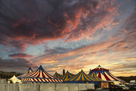 蓝色星光摄影照片_红白相间的马戏团帐篷顶着蓝色星光，顶着阳光明媚的蓝天和云彩