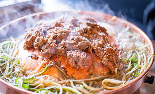 首尔韩国餐厅的牛肉烧烤烤肉，铜锅上的生活方式新鲜韩国美食，配上葱片，特写，复制空间