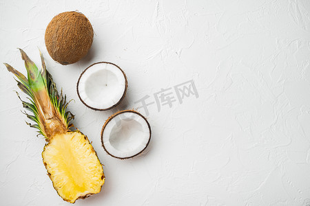 平铺菠萝摄影照片_由异国情调和热带水果、菠萝和椰子制成的创意布局，在白色石桌背景上，顶视图平躺，带有文本复制空间