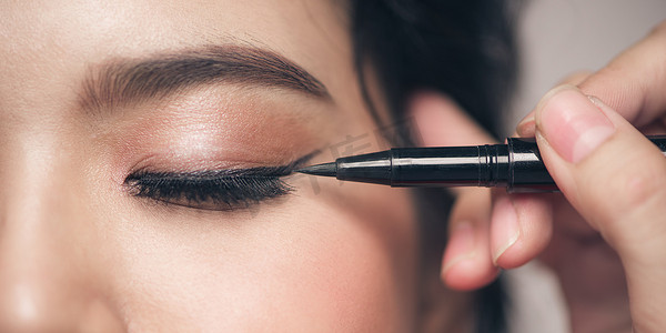 化妆师在女人的脸上画黑色眼线。