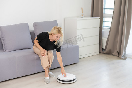 现代生活理念，女性放松，自动机器人吸尘器打扫房间，同时