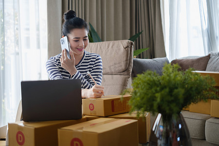 亚洲小企业主在家庭办公室通过智能手机检查订单。