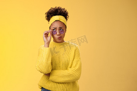 困惑不确定时尚的非洲裔美国女性创意设计师戴着头带毛衣太阳镜笑着折叠嘴唇管不确定有疑问皱着眉头抬头深思熟虑无法决定