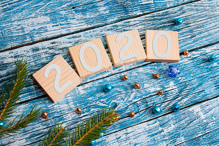 文字用木方块，2020 年新年，云杉树枝，闪亮的珠子，蓝色木质背景