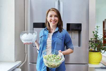 微笑的女人手里拿着一碗冰和一盘蔬菜沙拉