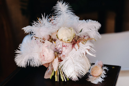 新娘的婚礼玫瑰花束，上面装饰着白色的羽毛和胸花