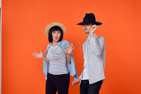 戴帽子的男人和女人摆出时尚橙色背景