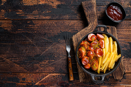 Currywurst 香肠与咖喱香料在 wursts 上供应法式炸薯条在平底锅中。