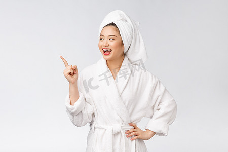 年轻女子的美丽肖像，手指指向空白的复制空间，穿着浴袍的亚洲美女。