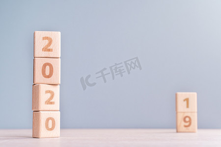 摘要2020年和2019年新年倒计时设计概念-木桌上的木块立方体和低饱和度蓝色背景，特写，复制空间。