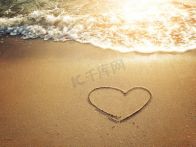 日落时分，在沙滩上画着白色气泡波的心