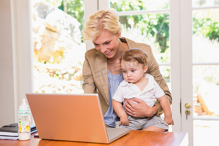 微笑的金发美女和儿子一起使用笔记本电脑
