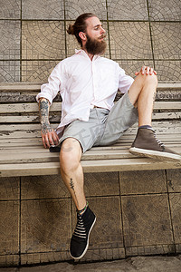 纹身肖像摄影照片_大胡子纹身时髦躺在长凳上