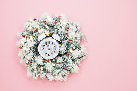 带装饰和闹钟的白色圣诞花环，背景为粉红色。
