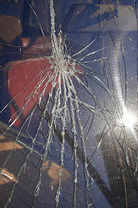 裂纹和玻璃碎片从被物体击中的窗户的撞击点辐射出来