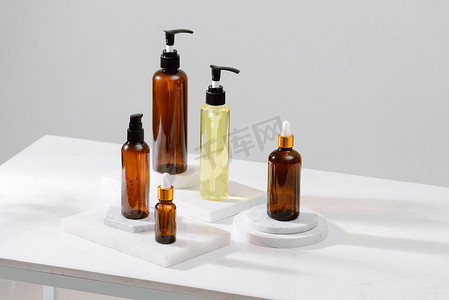 灰色混凝土桌上的棕色玻璃瓶中的水疗化妆​​品。