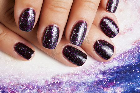 美甲时尚概念：指甲上有紫色指甲的女性手指，如宇宙、宇宙背景