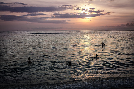 孩子们在傍晚夕阳下的海洋里游泳