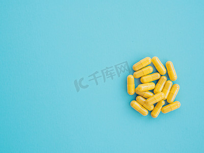 医药产品摄影照片_各种黄色医药产品、片剂、药丸、蓝色背景的胶囊。