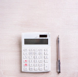 明亮木桌上的白色计算器和笔、财务利润分析和统计、投资风险概念、复制空间、顶视图平躺