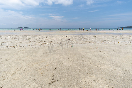 人们在海里畅游，在白沙滩上漫步。