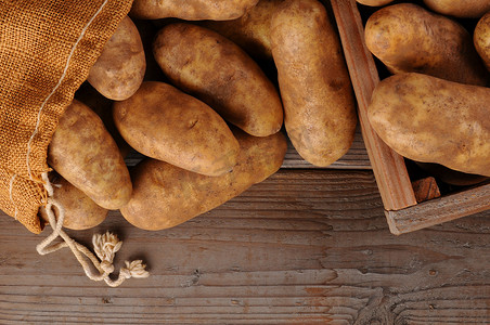 赤褐色摄影照片_质朴木材背景上的土豆
